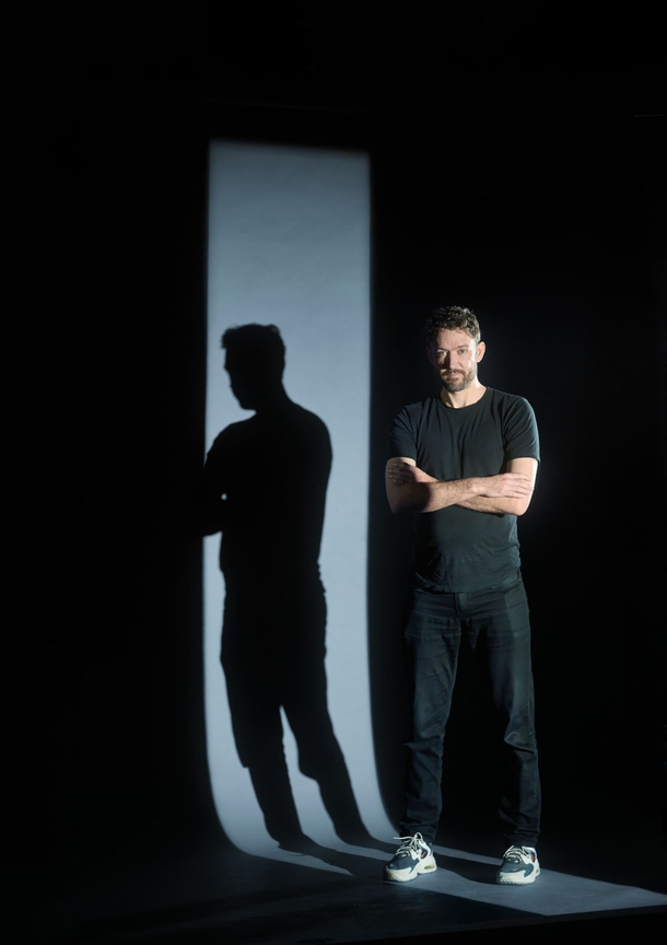 Front-End Developer Jay Bittner standing and staring at the camera with his own shadow in the background